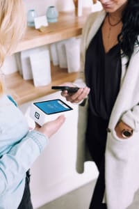 franchise-operations-roles Customer making a transaction in a store with device